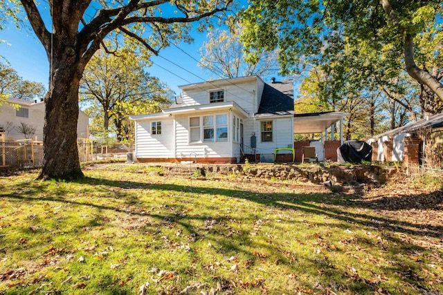 rear view of property with a lawn, fence, and a carport