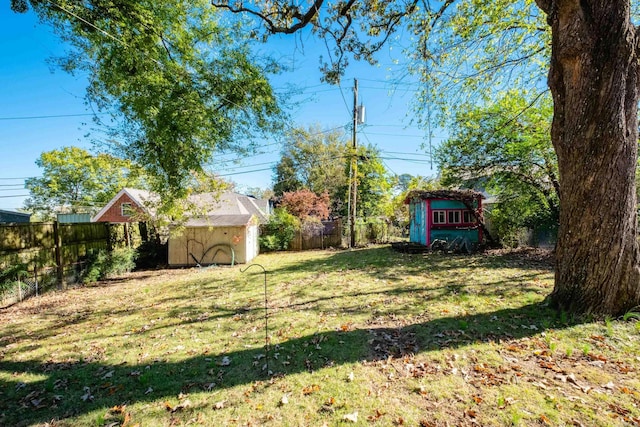 view of yard featuring a storage shed, a fenced backyard, and an outbuilding