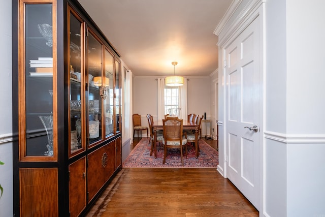 dining space featuring ornamental molding and dark wood-style flooring