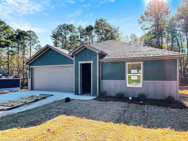 view of front of home with a garage, driveway, a shingled roof, and board and batten siding