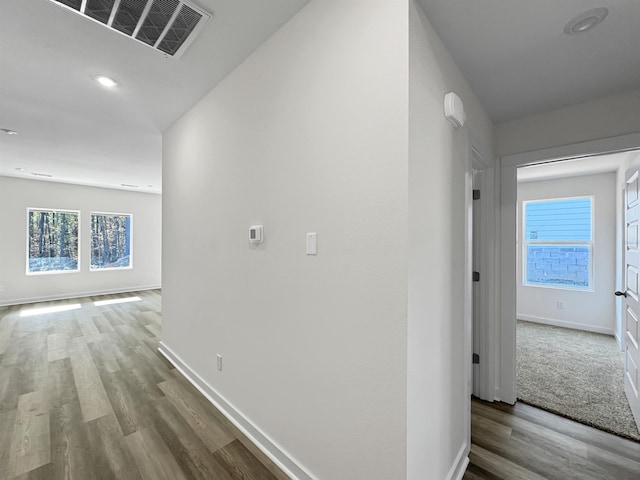 hall with recessed lighting, visible vents, baseboards, and wood finished floors