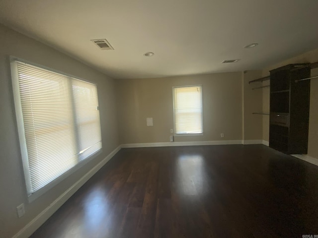 spare room featuring dark wood-type flooring, visible vents, and baseboards