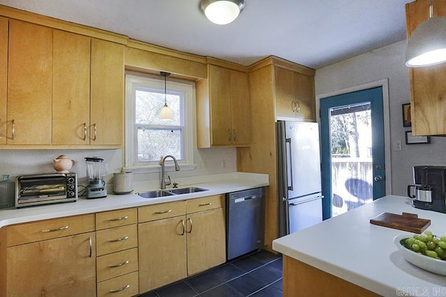 kitchen featuring dark tile patterned flooring, a sink, light countertops, freestanding refrigerator, and dishwasher