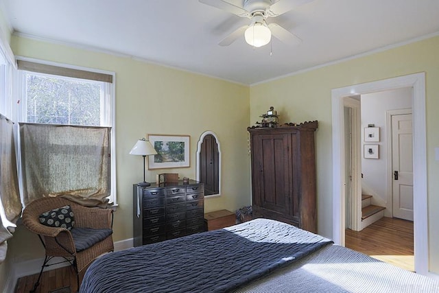 bedroom with baseboards, ceiling fan, ornamental molding, and wood finished floors