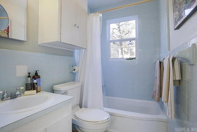 bathroom featuring toilet, shower / bath combo with shower curtain, tile walls, and vanity