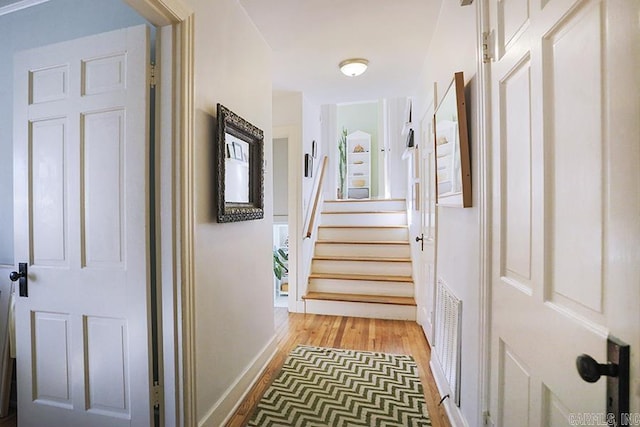 hallway with baseboards, stairway, visible vents, and light wood-style floors