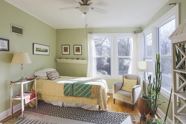 bedroom featuring baseboards, visible vents, a ceiling fan, wood finished floors, and crown molding