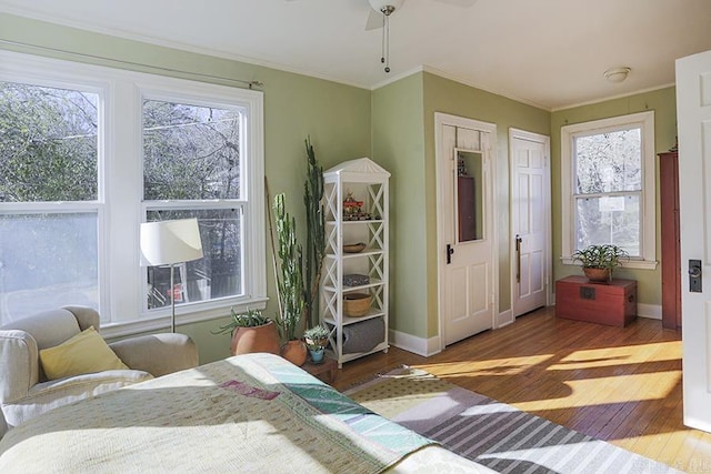 bedroom with ornamental molding, multiple windows, wood finished floors, and baseboards