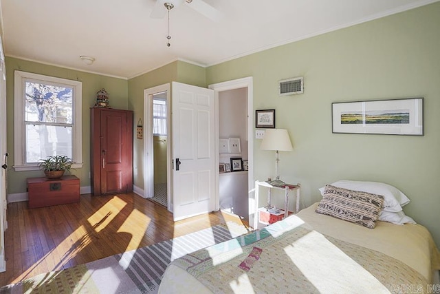 bedroom featuring visible vents, dark wood finished floors, a ceiling fan, baseboards, and ornamental molding