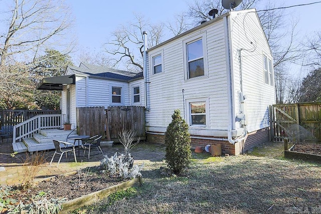 rear view of house with a deck, fence, and a vegetable garden