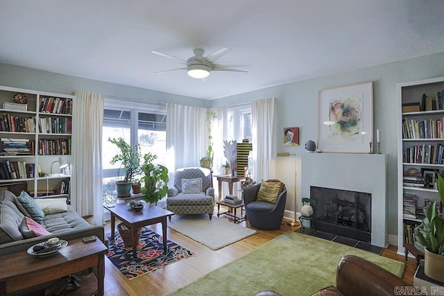 living room featuring light wood-style floors, a wealth of natural light, and a fireplace with flush hearth