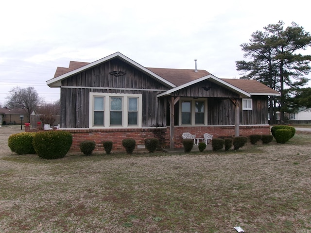 view of front of property featuring a front yard, board and batten siding, and brick siding