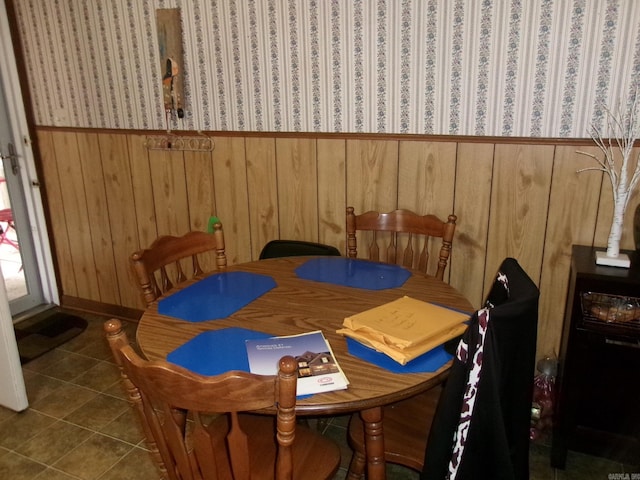 dining area with dark tile patterned flooring and wooden walls