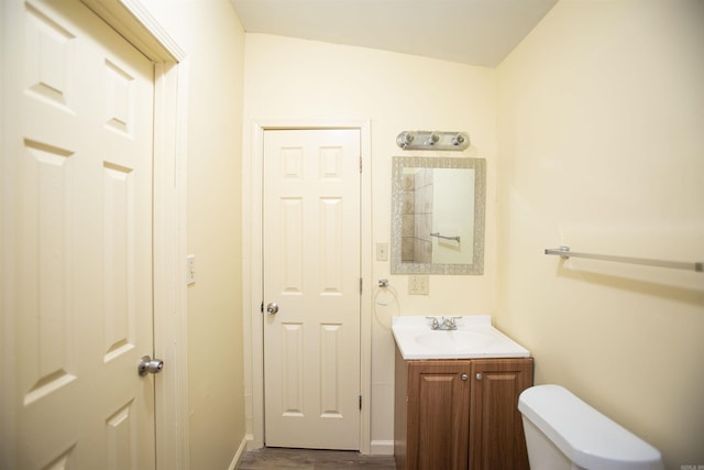 bathroom featuring wood finished floors, vanity, toilet, and baseboards