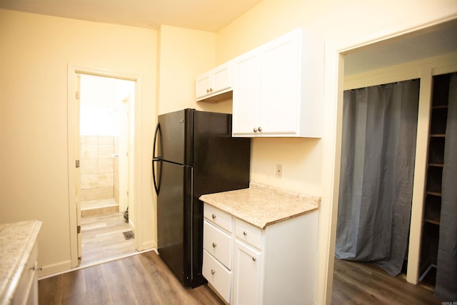 kitchen with wood finished floors, freestanding refrigerator, and white cabinets