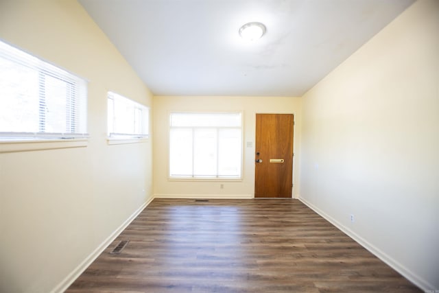 unfurnished room with vaulted ceiling, dark wood finished floors, visible vents, and baseboards