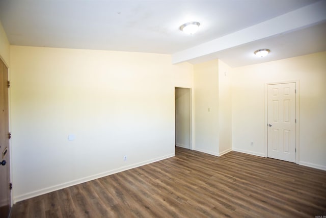 spare room featuring vaulted ceiling with beams, dark wood-type flooring, and baseboards