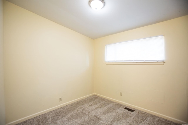 spare room featuring carpet floors, visible vents, and baseboards