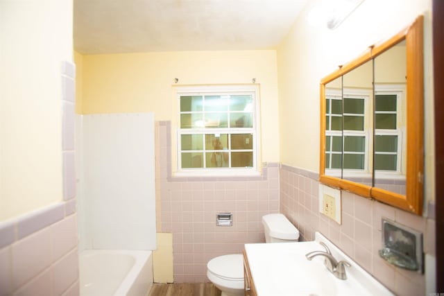 full bathroom with a wainscoted wall, tile walls, toilet, a bathing tub, and a sink