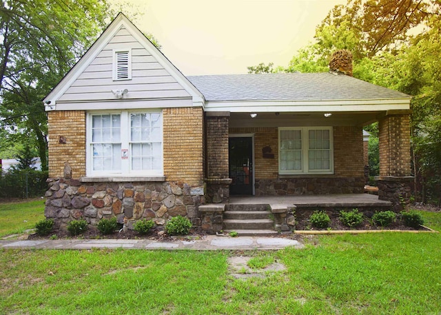 view of front of home featuring a yard, a porch, a chimney, and brick siding