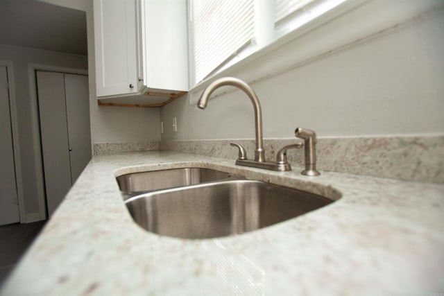 interior details with light stone counters, white cabinets, and a sink