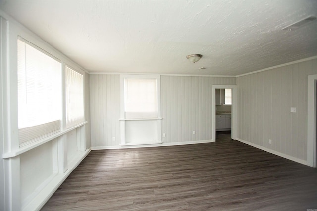 spare room featuring baseboards, dark wood-type flooring, and ornamental molding