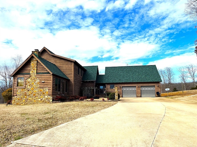 cabin with a garage, driveway, roof with shingles, a chimney, and a front yard