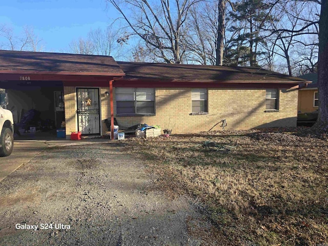 view of front facade featuring an attached carport, brick siding, and driveway