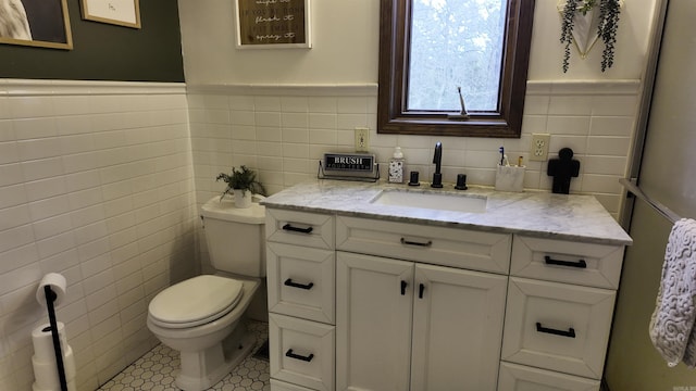 bathroom featuring toilet, wainscoting, tile walls, and vanity