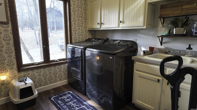 washroom featuring wallpapered walls, cabinet space, washer and clothes dryer, dark wood-style floors, and a sink