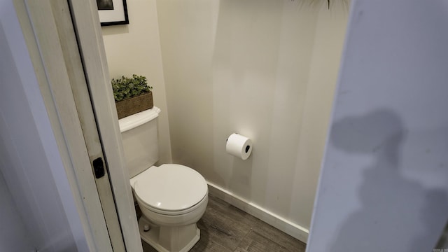 bathroom with toilet, baseboards, and wood finished floors