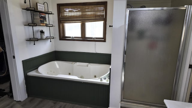 bathroom featuring a shower stall, a tub with jets, and wood finished floors