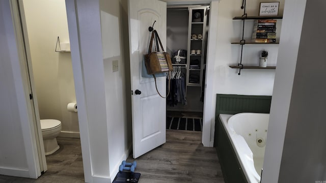 full bath featuring baseboards, toilet, a whirlpool tub, and wood finished floors