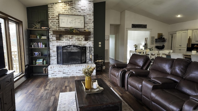 living area featuring dark wood-style floors, lofted ceiling, a brick fireplace, and a healthy amount of sunlight