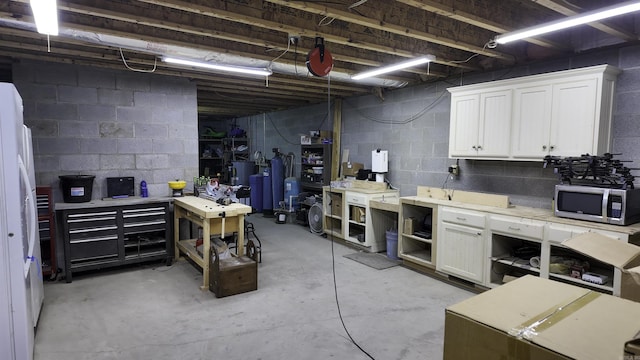 unfinished below grade area featuring a workshop area and freestanding refrigerator