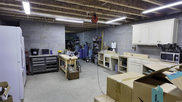 unfinished below grade area featuring a workshop area and freestanding refrigerator