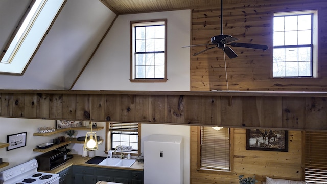 details featuring wooden walls, a skylight, a sink, a ceiling fan, and white range with electric stovetop