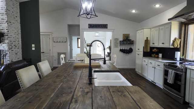 kitchen with range with two ovens, wall chimney exhaust hood, decorative light fixtures, vaulted ceiling, and a sink