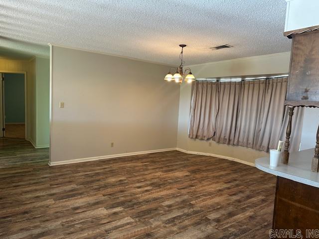 empty room with a textured ceiling, dark wood-type flooring, visible vents, and an inviting chandelier