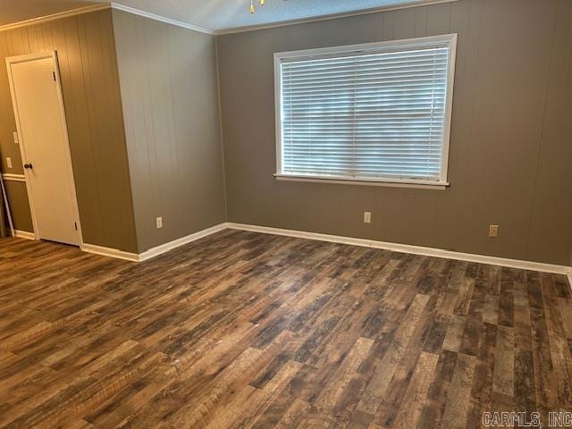 unfurnished room with baseboards, wood finished floors, and crown molding