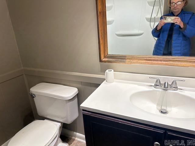 bathroom with a wainscoted wall, toilet, and vanity