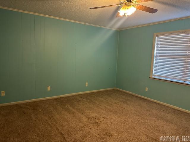 unfurnished room featuring a textured ceiling, ornamental molding, and carpet flooring