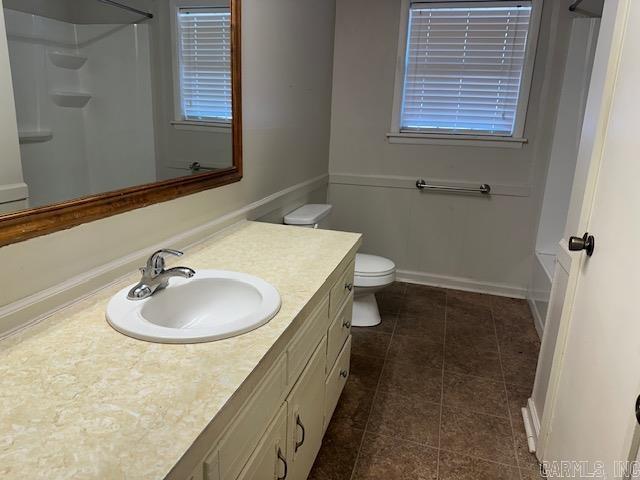 full bathroom featuring toilet, vanity, walk in shower, baseboards, and tile patterned floors