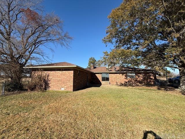 view of side of property featuring a chimney, a lawn, and brick siding