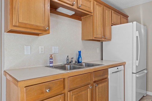 kitchen with brown cabinets, light countertops, a sink, a textured ceiling, and dishwasher