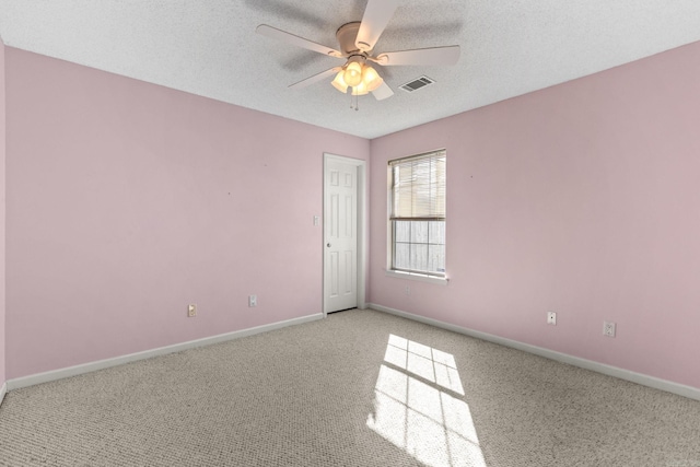 empty room featuring visible vents, light carpet, ceiling fan, a textured ceiling, and baseboards