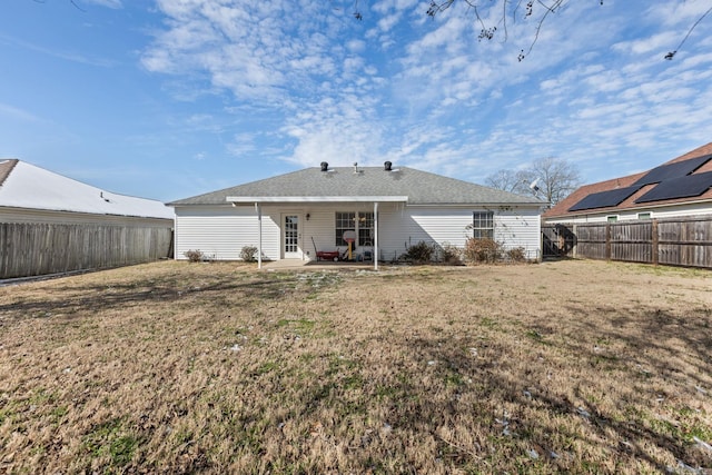 rear view of house featuring a fenced backyard, a lawn, and a patio