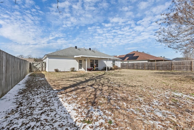 rear view of property featuring a fenced backyard and a yard