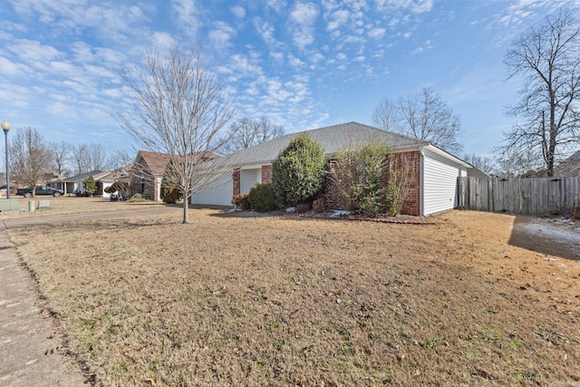 view of front facade featuring a garage, brick siding, a front lawn, and fence