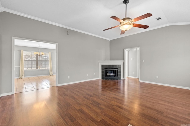 unfurnished living room featuring light wood finished floors, visible vents, a tiled fireplace, lofted ceiling, and ceiling fan with notable chandelier